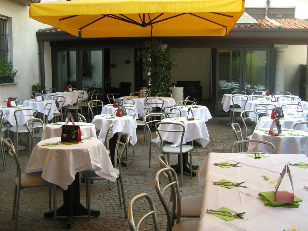 Il cortile con dehor, ombrelloni gialli e tavoli